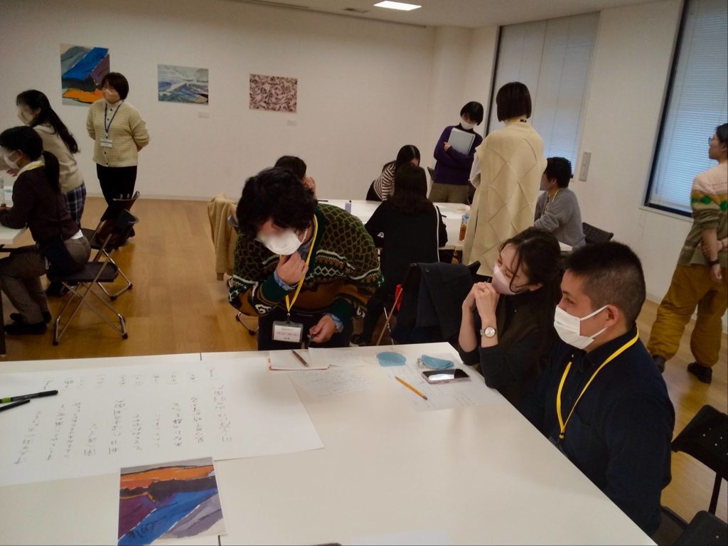 3つのグループに分かれて、参加者同士が白いテーブルを前にディスカッションをしている様子。