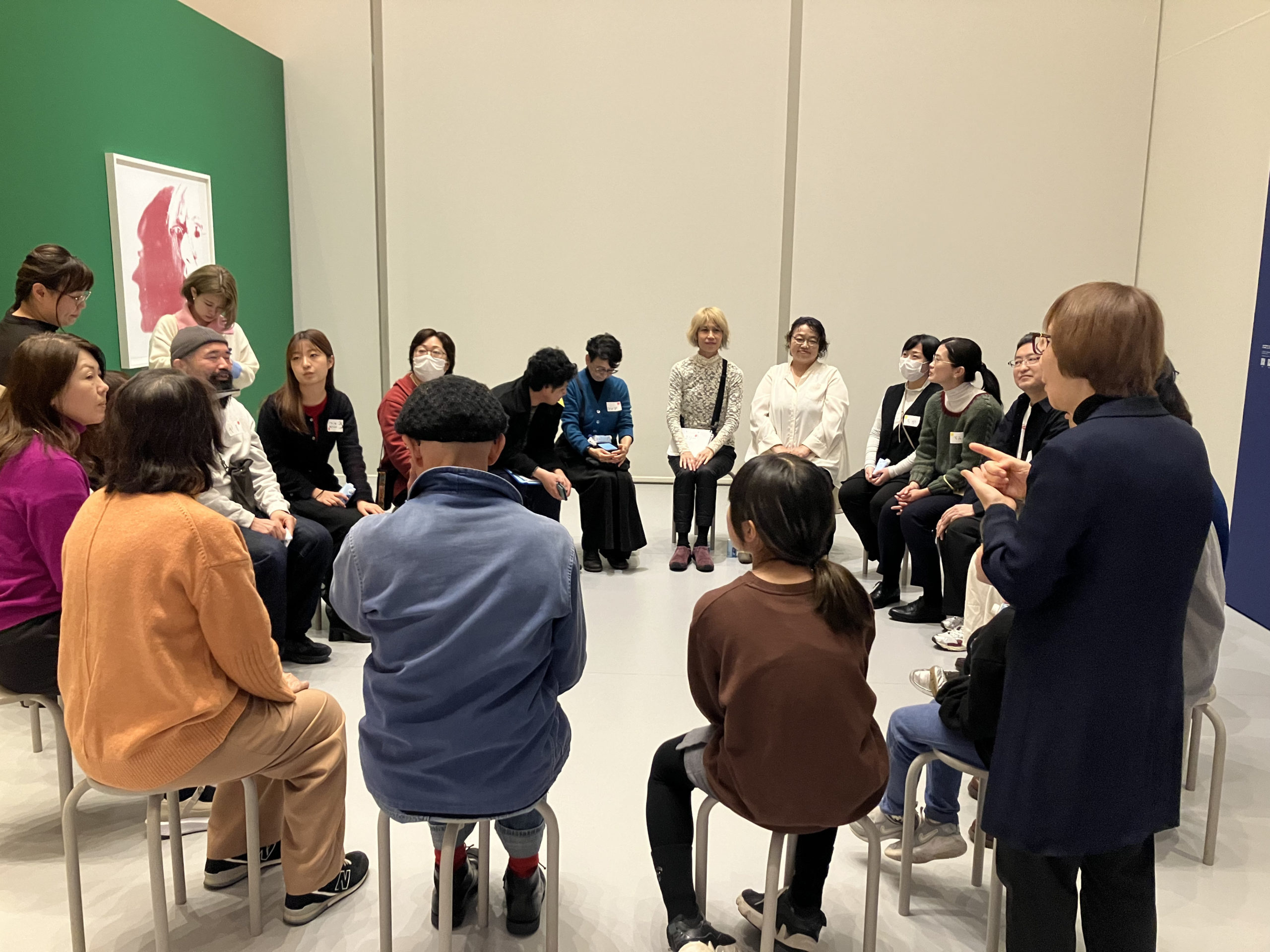 参加者が円になって腰掛け、鑑賞ワークショップの感想を共有している様子の写真。