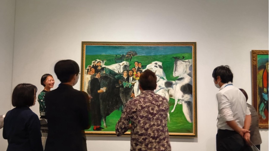 絵画の前に5から6人の研修参加者が集まって鑑賞をしている様子の写真。